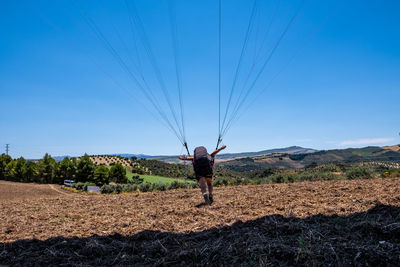 Rear view of man standing on field with parachute against sky