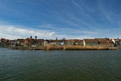 Houses by sea against sky in city