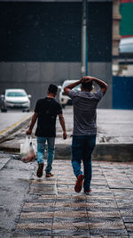 Rear view of people walking on street in rain