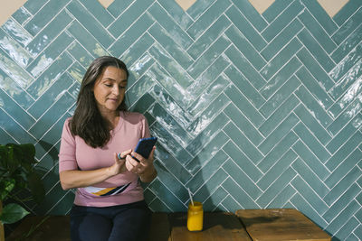Young woman using mobile phone while standing on camera