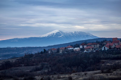 Houses on townscape by mountains against sky