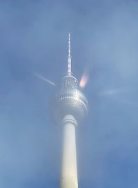 Low angle view of communications tower and building against sky