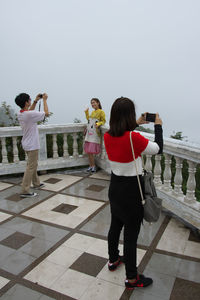 Rear view of people standing on tiled floor against clear sky