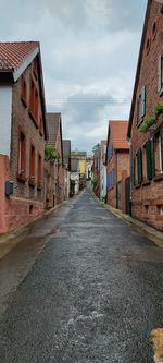 Empty road amidst buildings against sky