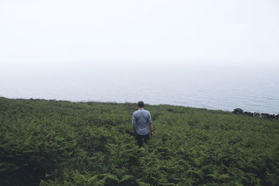 Rear view of man looking at sea against sky