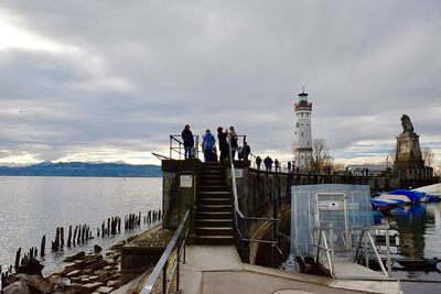 People at observation point against cloudy sky