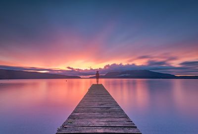 Pier on lake at sunset