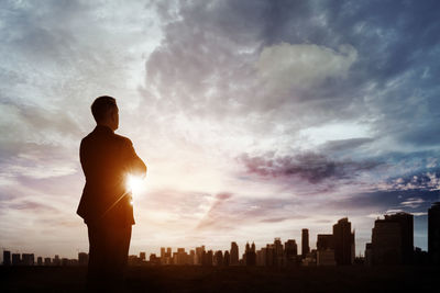 Silhouette of man looking at city buildings against sky