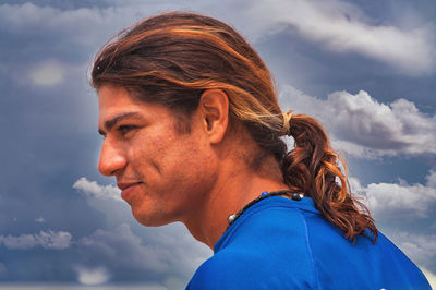 Portrait of young woman looking away against sky