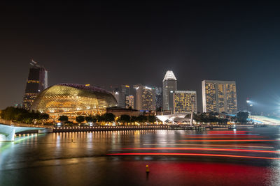 Illuminated city buildings by river at night