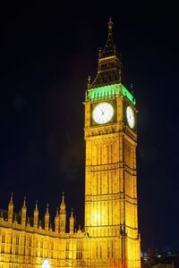 Low angle view of clock tower at night