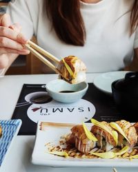 Close-up of hand holding food in plate on table