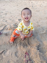 High angle portrait of cute baby boy on sand at beach