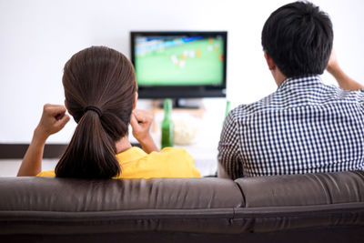 Rear view of people watching soccer at home 