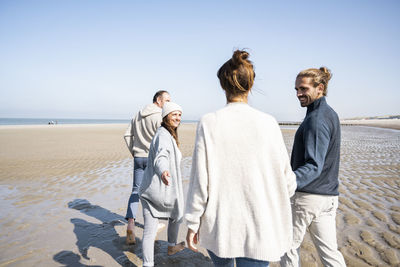 Mature and young couple holding hands while walking at beach