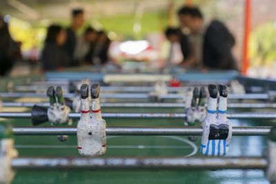 Close-up of figurines on foosball table with friends playing in background