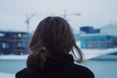 Rear view of woman against sky during winter