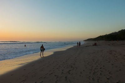 Scenic view of beach against clear sky during sunset