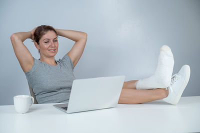 Young woman using mobile phone while sitting on table