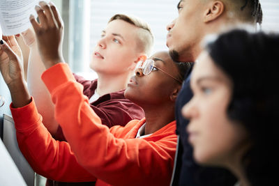 Male and female university students checking test results on bulletin board