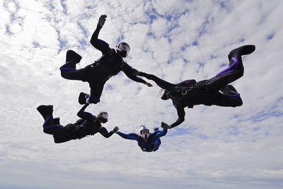 Low angle view of people jumping against sky