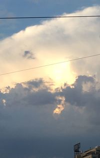 Low angle view of power lines against cloudy sky