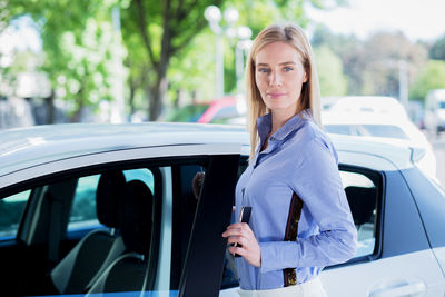 Portrait of woman standing by car