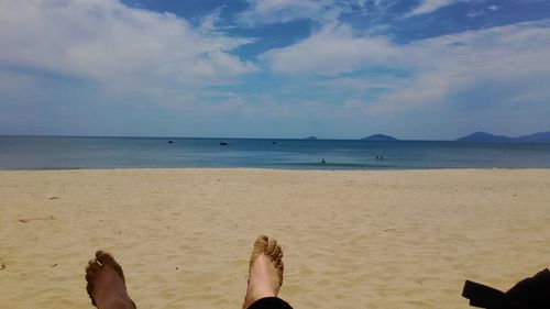 Low section of man on beach against sky