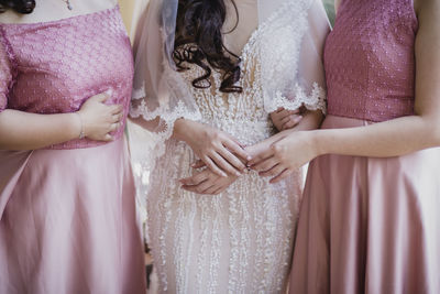 Midsection of bride standing with bridesmaid