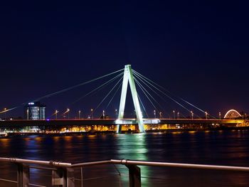 Illuminated bridge over river against clear sky at night