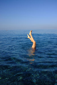 Man swimming in sea against clear sky