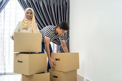 Couple holding cardboard boxes while standing at new home