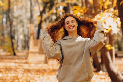 Young woman standing against trees