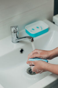 Cropped hand of person washing hands in sink