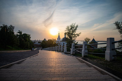 Pier over river against sky during sunset