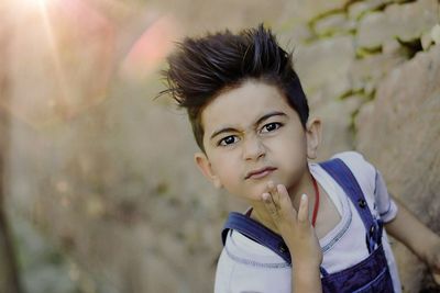 High angle portrait of boy making face on rock