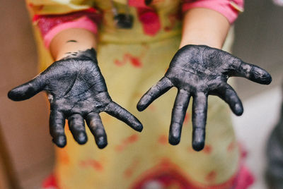 Midsection of woman showing black painted messy hands