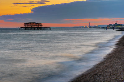 The beach in brighton, england, after sunset with the ruin of the old pier in the back