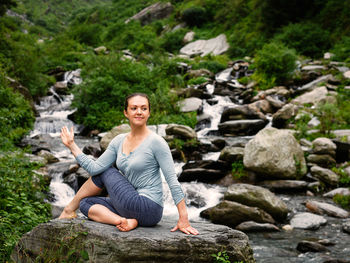 Man sitting on rock by waterfall