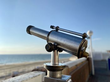 Close-up of coin-operated binoculars by sea against sky