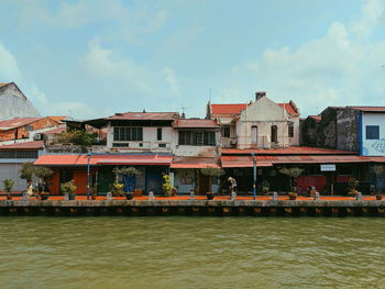 Buildings by river against sky