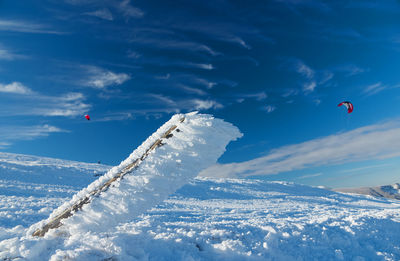 People flying kite in snow against sky