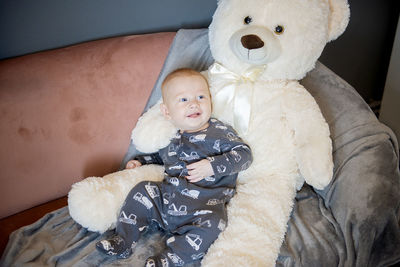 High angle view of boy with stuffed toy on sofa