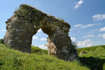 Old ruin on grassy landscape against sky