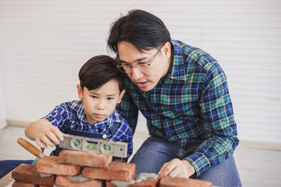 Father teaching son to make brick wall at workshop