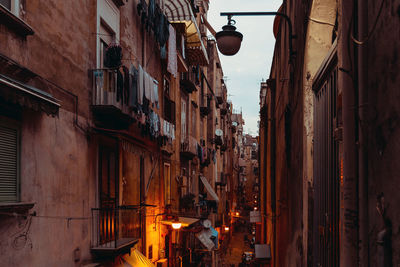 Narrow alley amidst buildings in city at dusk