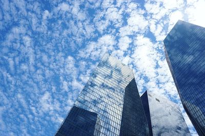 Low angle view of tall buildings against clouds