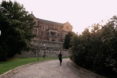 Rear view of girl walking on street against building