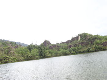 Scenic view of river by mountains against clear sky