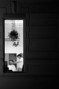 Rear view of woman standing by window